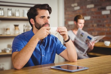  Young man having cup of coffee using tablet