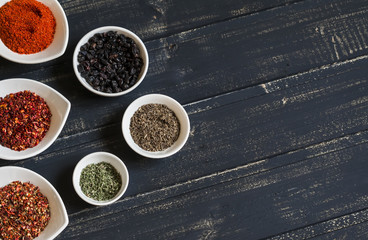 assorted spices in white bowls on a dark wooden surface - Powered by Adobe