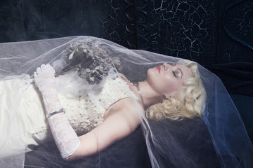 Sleeping Beauty. Beautiful lifeless bride in white dress lying o