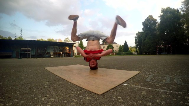 Crazy boy spins on his head on the street
