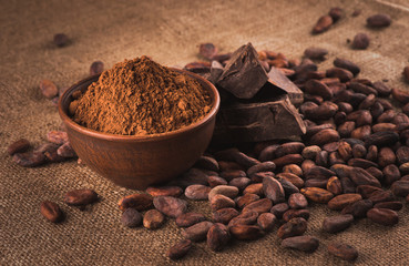 Raw cocoa beans, clay bowl  with cocoa powder, chocolate on sack