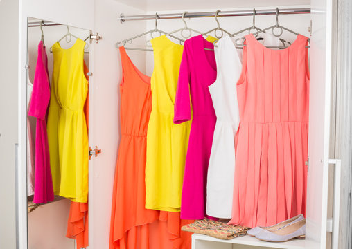 row of bright colorful dress hanging on coat hanger, shoes and h