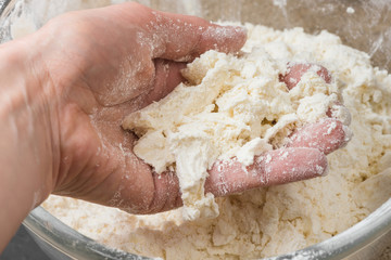 a hand mixing the flour and butter in a glass bowl