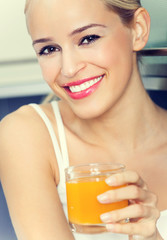 Portrait of young woman with orange juice, indoors
