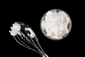 beaten eggs whites with whisk isolated on black background
