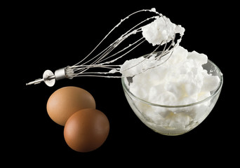 whipping eggs with whisk and eggs isolated on black background