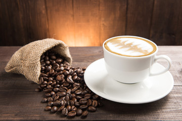 Coffee cup and coffee beans on wooden background.
