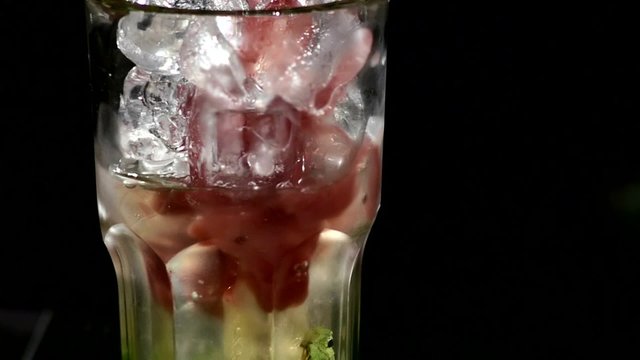 A cube of ice falling into a glass of water. close up. slow