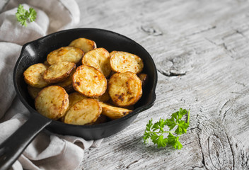 baked potatoes in the pan on a light wooden surface