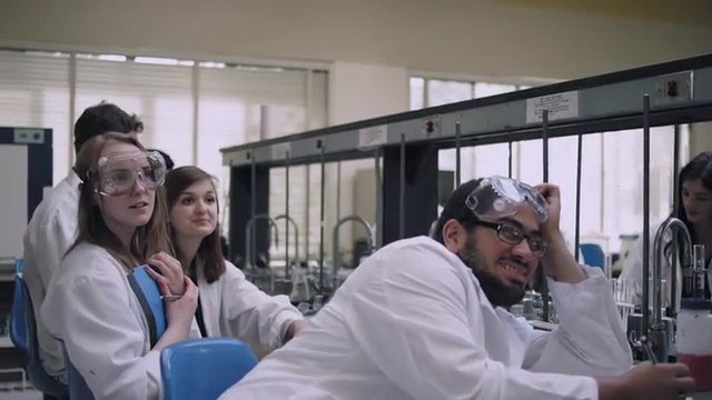 Students In A Science Lab Listen To Their Professor And Take Notes
