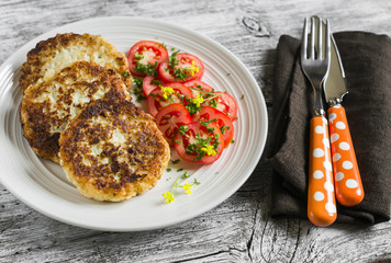 delicious vegetarian cabbage cutlets and fresh tomatoes on a light plate  on a light wooden surface