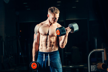 Athlete muscular bodybuilder training back with dumbbell  in the