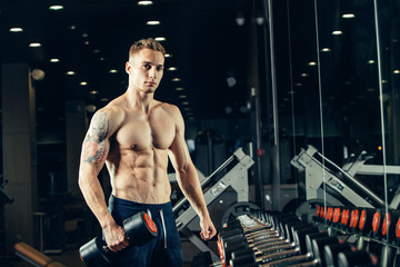 Fototapeta na wymiar Male athlete with a dumbbell in the gym lean on row