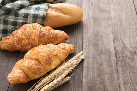 Freshly baked croissants and baguette on wooden table