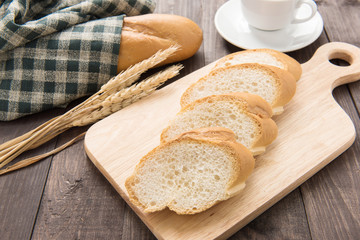 Freshly baked baguette and coffee cup on wooden table