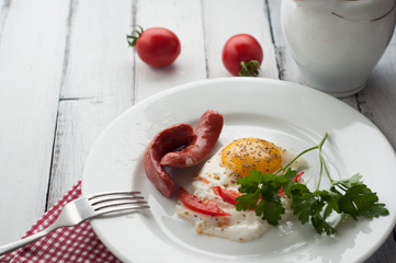 scrambled eggs on a plate with pieces of tomato and sausage