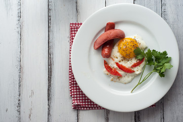 scrambled eggs on a plate with pieces of tomato and sausage