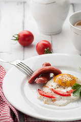 scrambled eggs on a plate with pieces of tomato and sausage