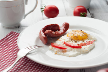 scrambled eggs on a plate with pieces of tomato and sausage