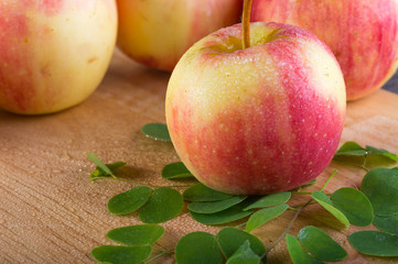 wet fuji apple on wood chop block and on wood table