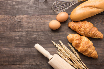 Fototapeta na wymiar Freshly baked croissants, baguette and eggs on wooden background