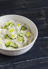 risotto with zucchini in a white bowl on a dark wooden surface