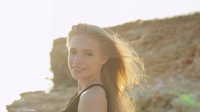 Beautiful blonde with long hair wearing a black dress laughing
