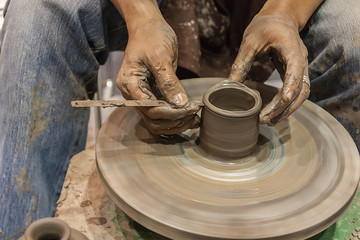 Hands working on pottery wheel, closeup retro style tone