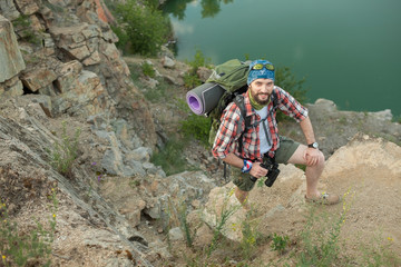 Young caucasian man with backpack climbing the rock
