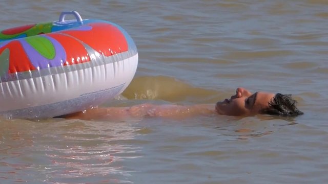 A young man swims with inflatable circle