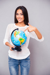 Happy young woman pointing finger at globe