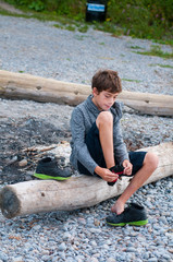 child sitting on a rocky beach putting on his shoes
