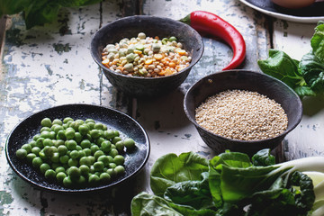 Quinoa Burger ingredients: quinoa, mangold, dry grain mix, chili pepper, eggs green peas basil on white rustic board