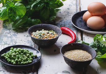 Quinoa Burger ingredients: quinoa, mangold, dry grain mix, chili pepper, eggs green peas basil on white rustic board