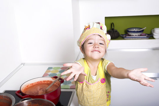 Little girl cooking tomato sauce.