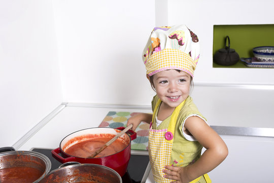 Little girl cooking tomato sauce.