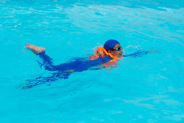 Asia boy swimming in the blue pool.