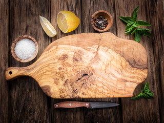 Olive cutting board and spices on a wooden table.