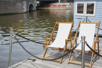 White deck chairs near the canal in Amsterdam