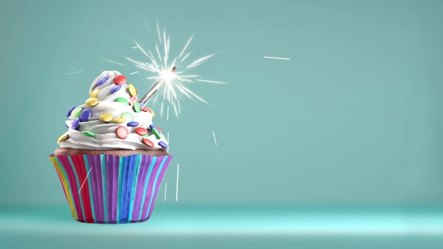Delicious cupcake with a glittering sparkler and smarties on a whipped cream. Copy space available. 4k video.
