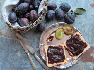 Bread with plum jam on silver plate with rustic cutlery