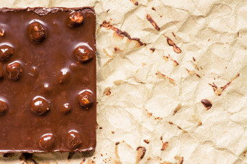 Chocolate bar with hazelnuts on paper