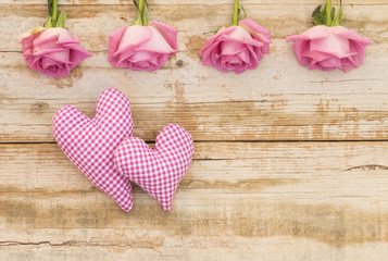 Obraz na płótnie Canvas Zwei Herzen romantisch mit rosa Rosen auf Holz Hintergrund