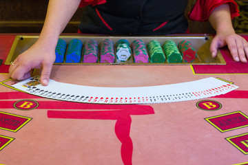 Casino dealer (croupier) spreaded the deck of cards on the Poker table.