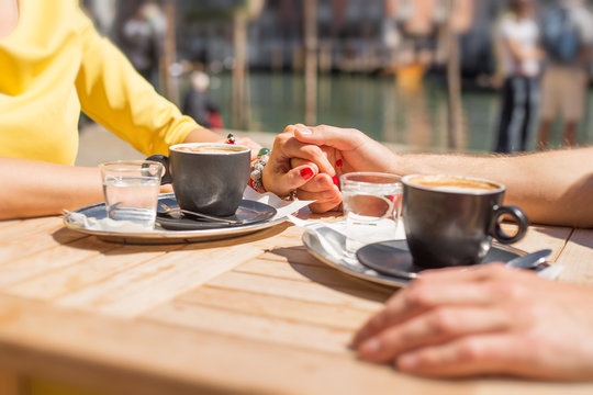 Couple holding hands and drinking coffee in cafe outdoors
