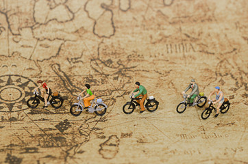 miniature people ride bicycle on vintage map