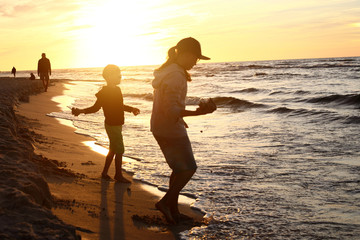 Wakacje nad morzem. Dzieci bawią się na brzegu morza podczas zachodu słońca - obrazy, fototapety, plakaty