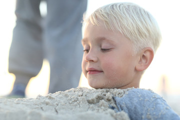 Dziecko na plaży.Wesoły chłopiec bawi się w piasku na plaży - obrazy, fototapety, plakaty
