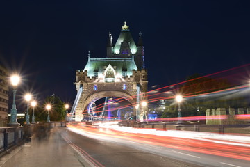 World famous Historic Tower Bridge in London, UK at night with light trail of red bus and cars, long exposure artistic shot