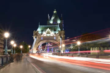 Fotobehang World famous Historic Tower Bridge in London, UK at night with light trail of red bus and cars, long exposure artistic shot © singhlens